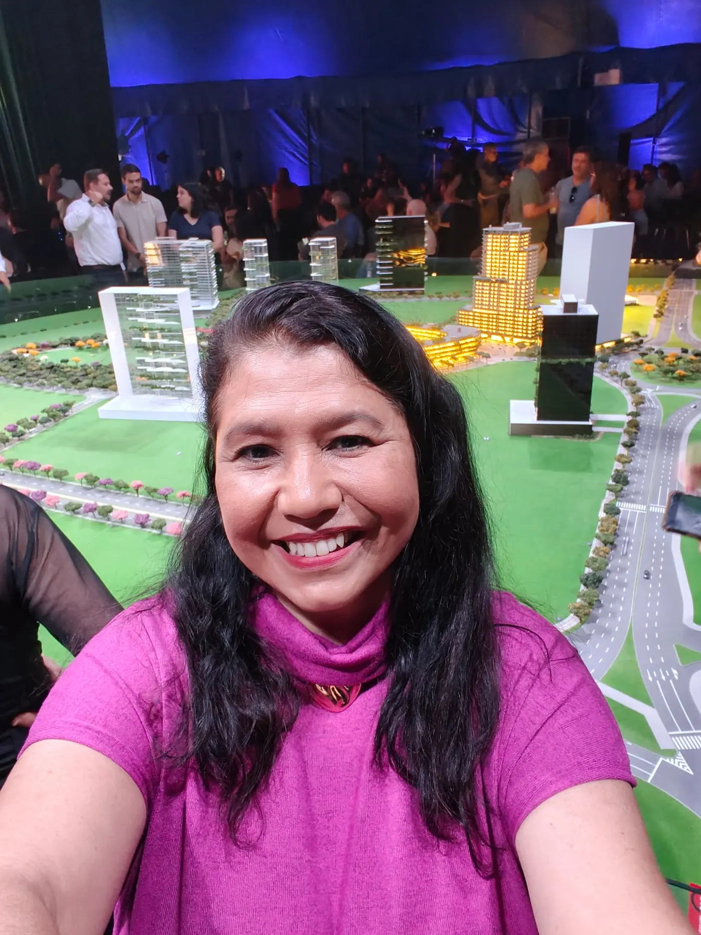 Mary Moura no Una Talks, com a maquete iluminada do Parque Una ao fundo